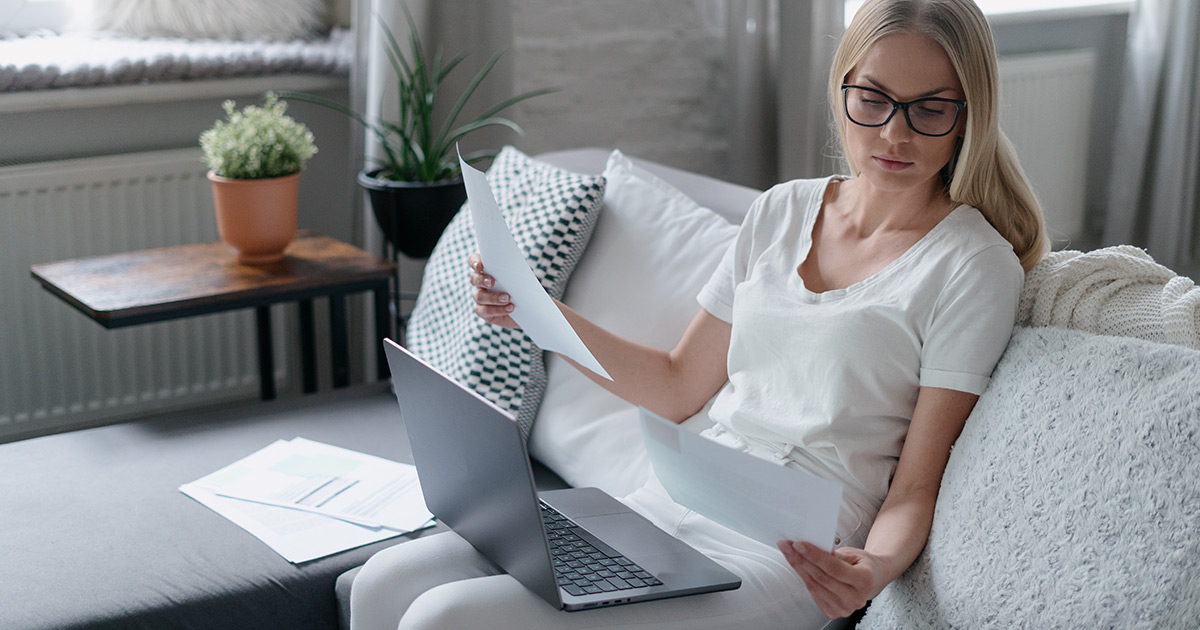  femme regardant des documents et assise sur un canapé