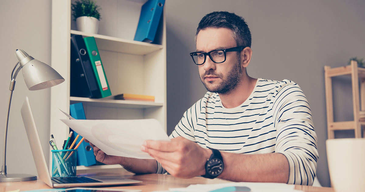 Un homme mûr sérieux travaille avec du papier au bureau.