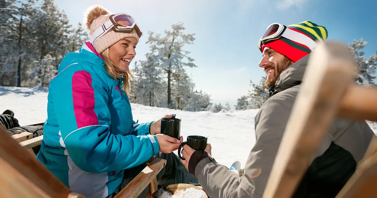 Amis souriants se détendant sur des chaises au sommet de la montagne par une journée ensoleillée. Vue arrière