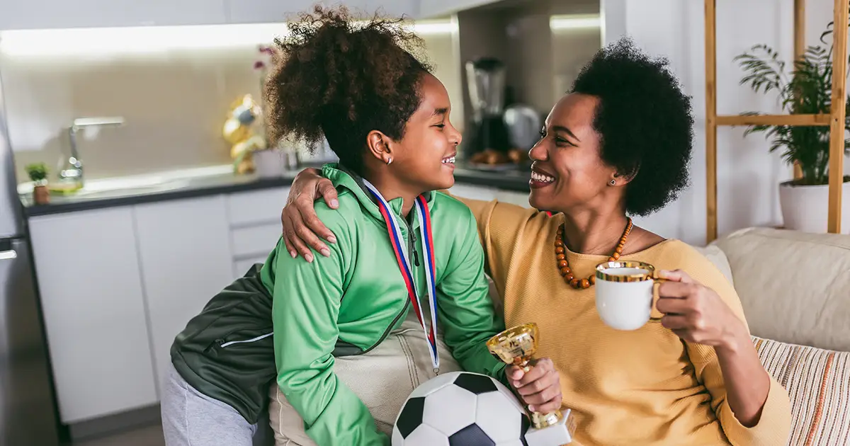 Une mère fière et excitée de voir sa fille médaille et trophée à la main après un match de football