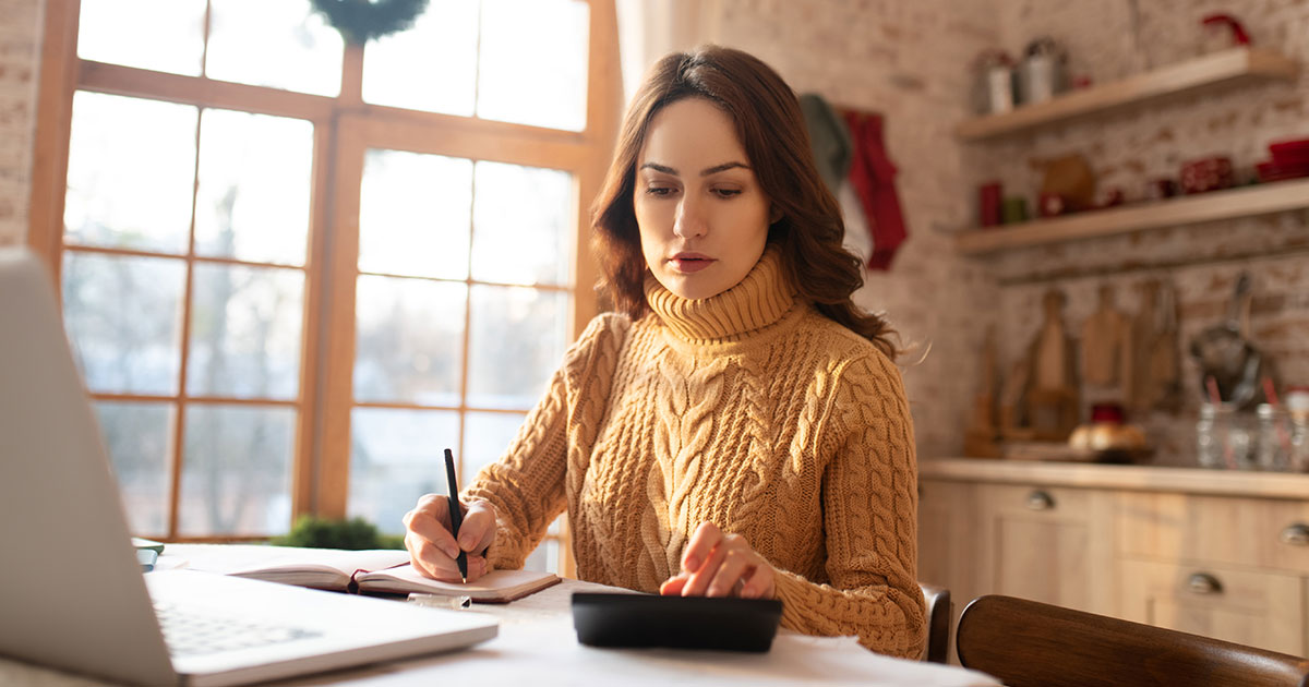 Femme budgétisant avec calculatrice pendant la saison de Noël.