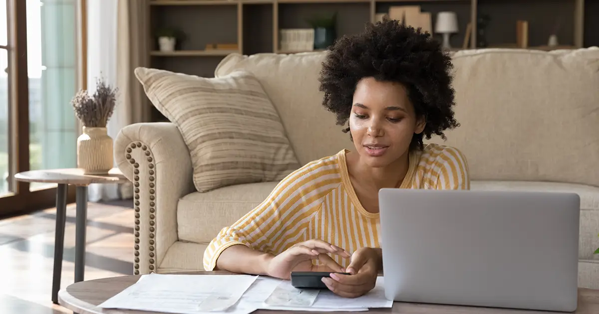  une femme fait des calculs sur une calculatrice pour payer ses factures