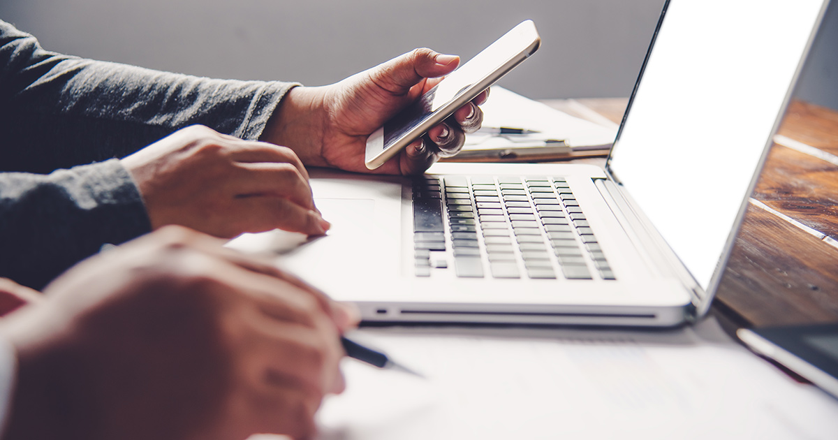 Travailler avec un ordinateur portable et un smartphone dans un bureau à aire ouverte.