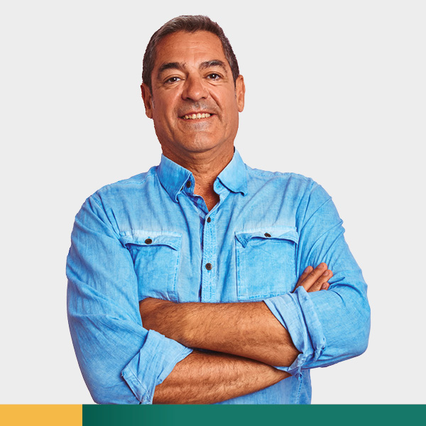 Middle aged man in blue shirt smiling with arms crossed